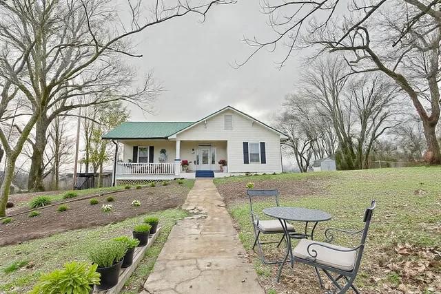 ranch-style house with french doors, covered porch, and a front lawn