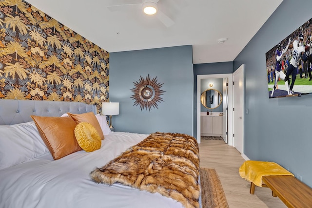 635 7th Ave S Unit 211, Nashville, TN 37203 - bedroom with wallpapered walls, wood finished floors, ensuite bath, ceiling fan, and baseboards