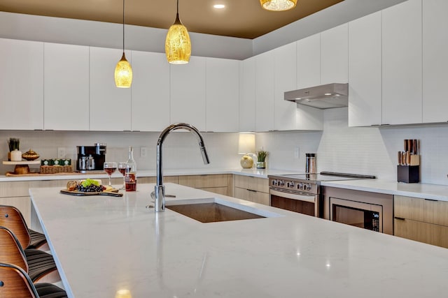 635 7th Ave S Unit 211, Nashville, TN 37203 - kitchen featuring modern cabinets, a sink, under cabinet range hood, a breakfast bar area, and recessed lighting