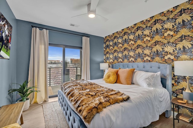635 7th Ave S Unit 211, Nashville, TN 37203 - bedroom with an accent wall, access to exterior, wallpapered walls, wood finished floors, and ceiling fan