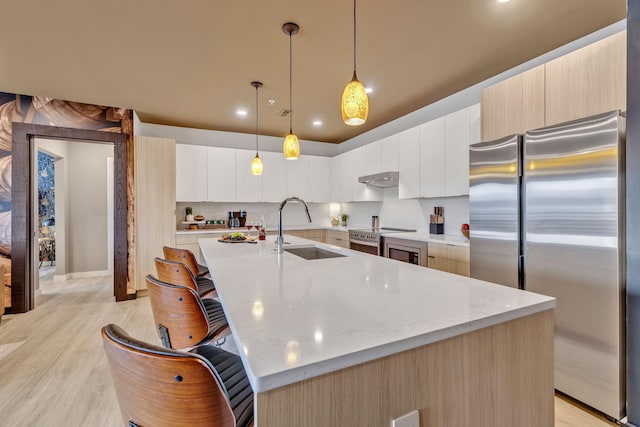 635 7th Ave S Unit 211, Nashville, TN 37203 - kitchen featuring freestanding refrigerator, a sink, modern cabinets, a large island with sink, and light wood-type flooring