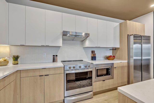 635 7th Ave S Unit 211, Nashville, TN 37203 - kitchen featuring stainless steel appliances, under cabinet range hood, modern cabinets, and tasteful backsplash