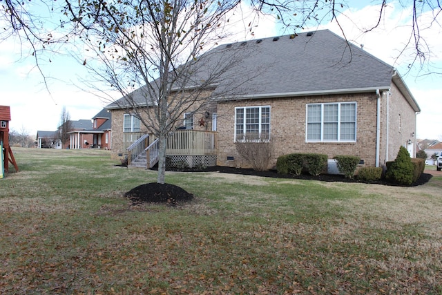 rear view of house with a shingled roof, crawl space, brick siding, and a yard