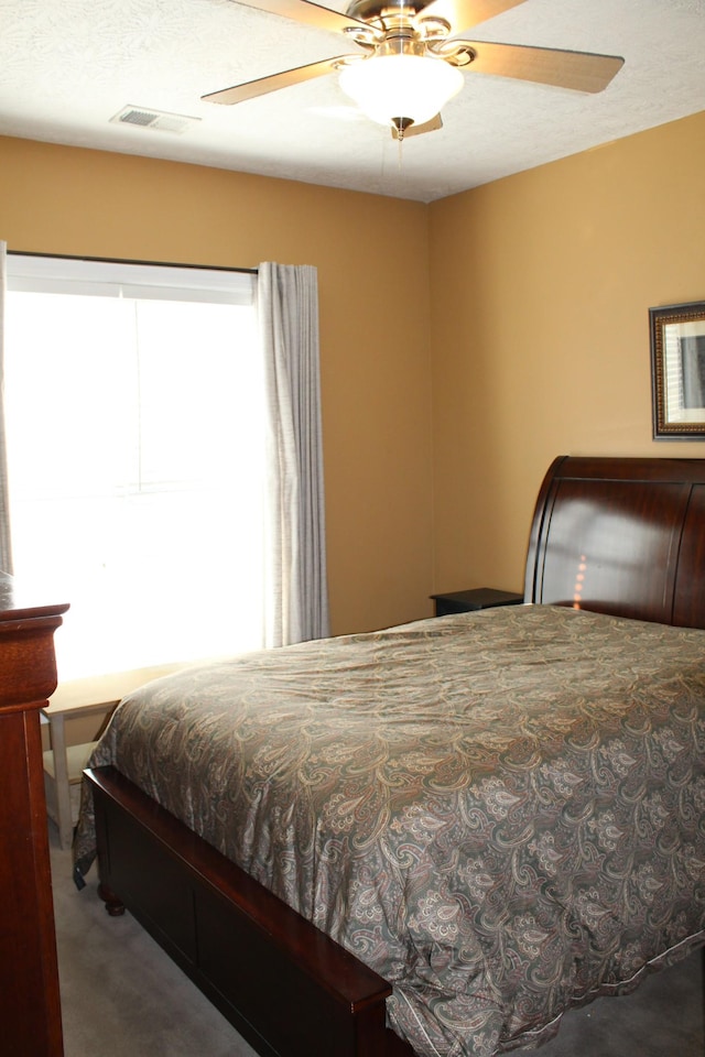 carpeted bedroom with ceiling fan, visible vents, and a textured ceiling