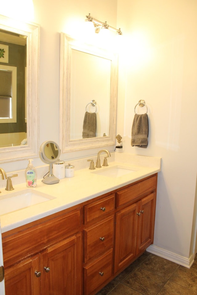 full bath with double vanity, baseboards, and a sink