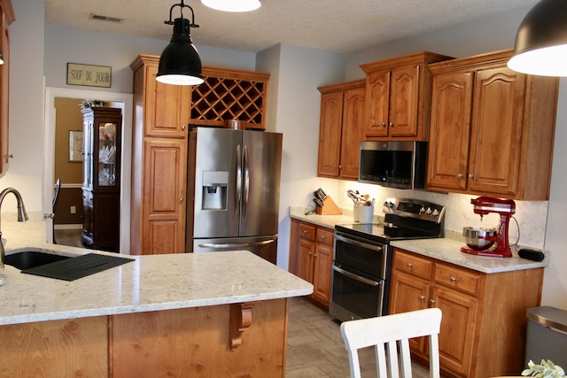 kitchen with stainless steel appliances, a sink, visible vents, light stone countertops, and pendant lighting