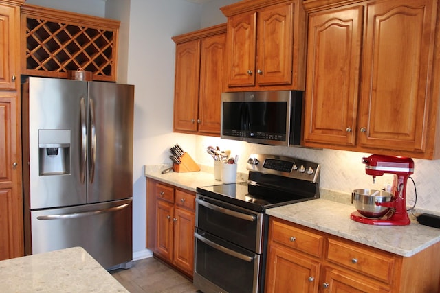 kitchen featuring brown cabinetry, tasteful backsplash, and stainless steel appliances