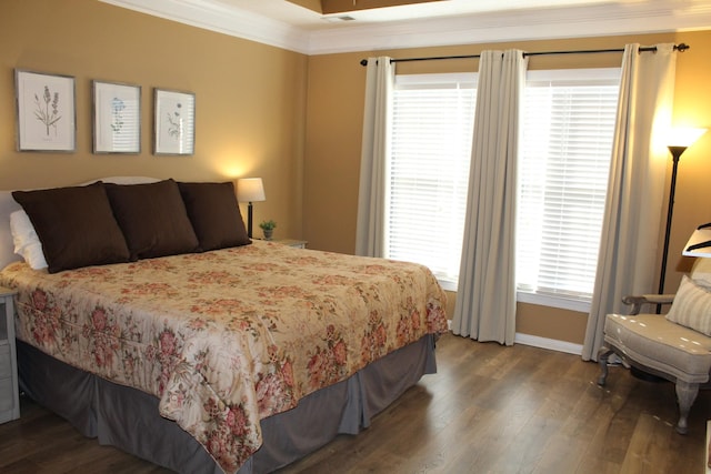 bedroom featuring baseboards, wood finished floors, and crown molding