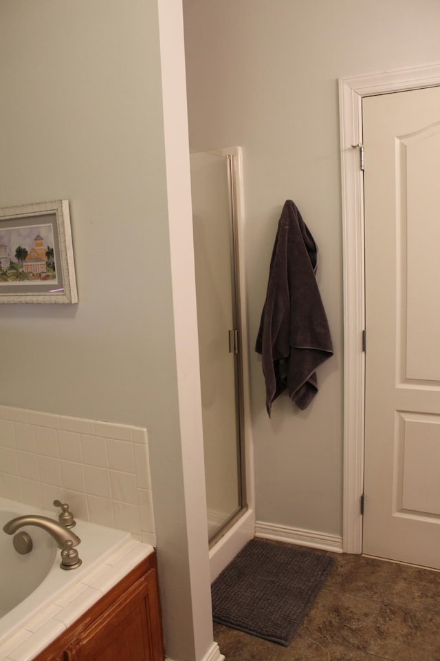 bathroom featuring a stall shower, a garden tub, and baseboards