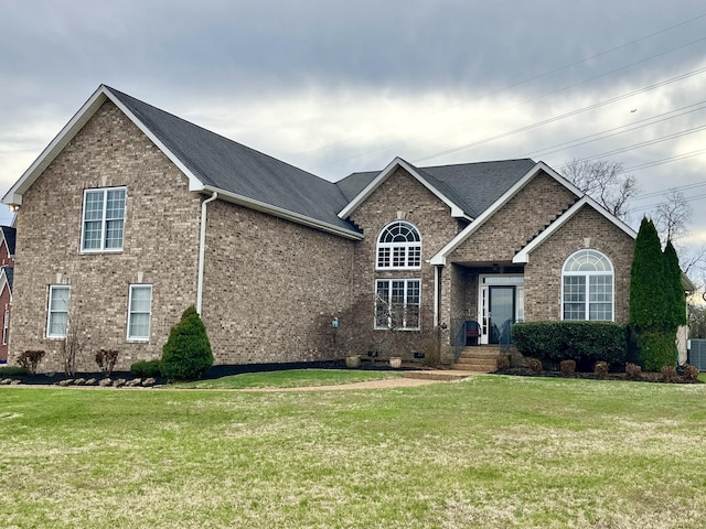 view of front of property with brick siding, central AC unit, a front yard, and a shingled roof