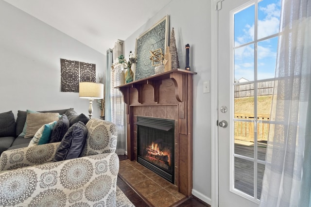 tiled living room with a tile fireplace and vaulted ceiling