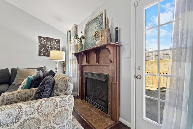 living room with a tile fireplace, vaulted ceiling, and dark tile patterned flooring