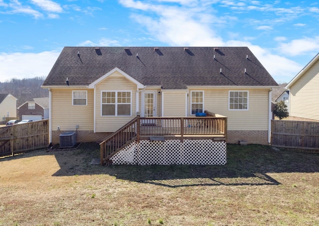 rear view of house featuring a wooden deck, central AC unit, and a lawn