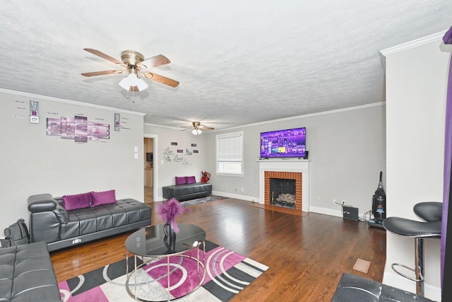 living room featuring a fireplace, crown molding, wood-type flooring, and a textured ceiling