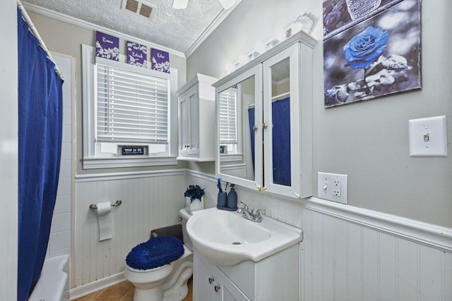 full bathroom with vanity, ornamental molding, a textured ceiling, toilet, and shower / bath combo with shower curtain