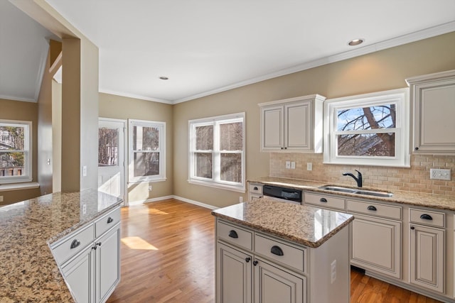 kitchen with dishwashing machine, a center island, sink, and light stone counters