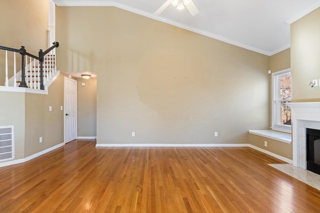 unfurnished living room featuring a fireplace, crown molding, and wood-type flooring