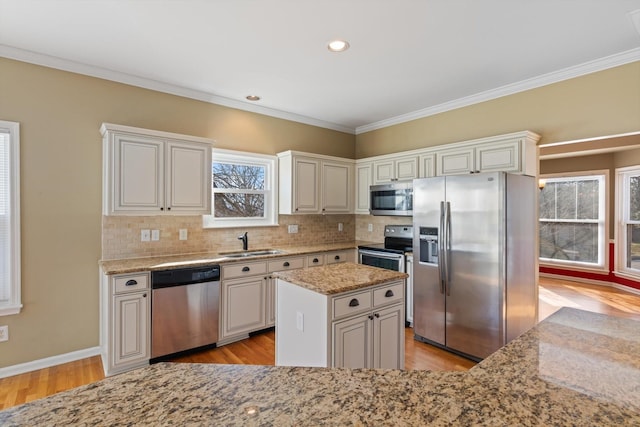 kitchen featuring appliances with stainless steel finishes, sink, white cabinetry, a kitchen island, and light stone countertops