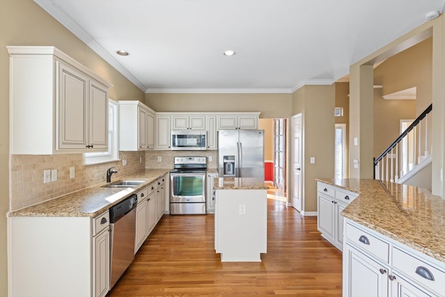 kitchen with a kitchen island, sink, stainless steel appliances, and light stone countertops