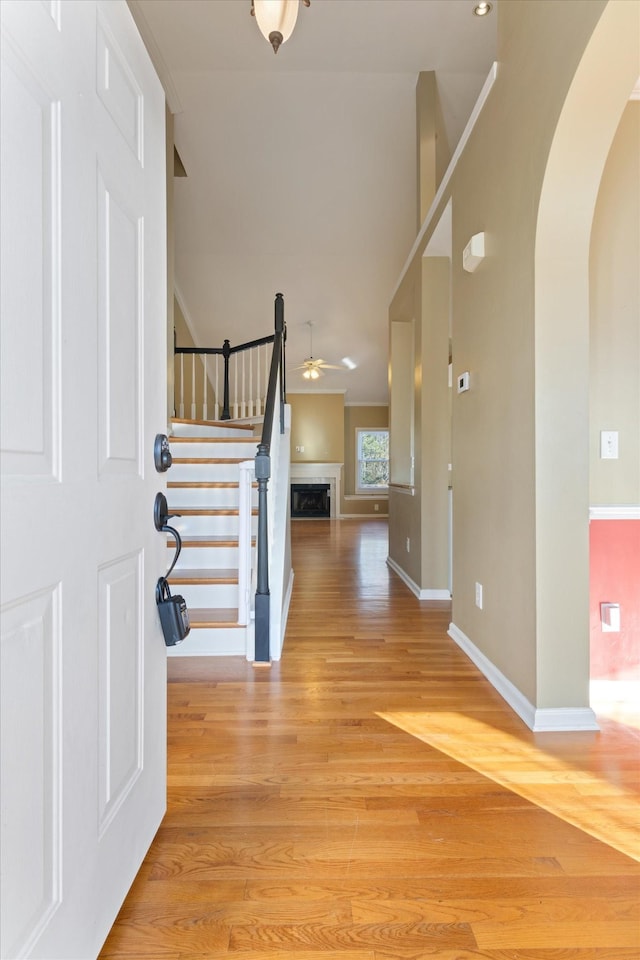 entryway with a towering ceiling, ceiling fan, and light hardwood / wood-style flooring