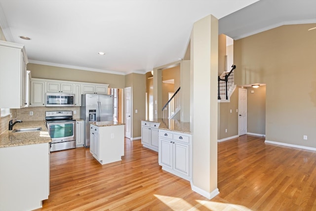 kitchen featuring a kitchen island, light stone countertops, sink, appliances with stainless steel finishes, and white cabinets