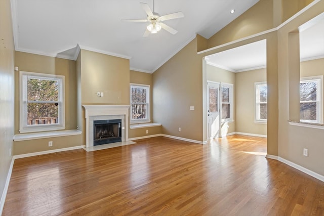 unfurnished living room with a premium fireplace, vaulted ceiling, crown molding, and wood-type flooring