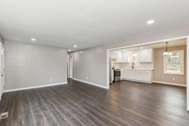 unfurnished living room with an inviting chandelier, sink, and dark wood-type flooring