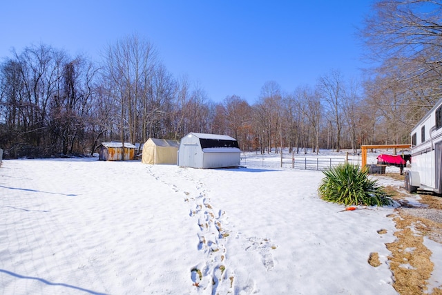 yard layered in snow featuring a storage unit