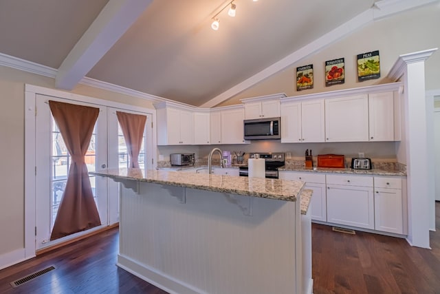 kitchen featuring white cabinetry, appliances with stainless steel finishes, light stone countertops, and a kitchen island with sink