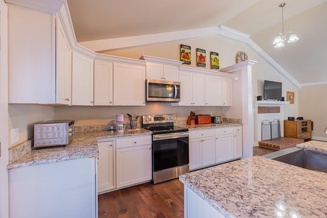 kitchen with hanging light fixtures, white cabinetry, appliances with stainless steel finishes, and lofted ceiling