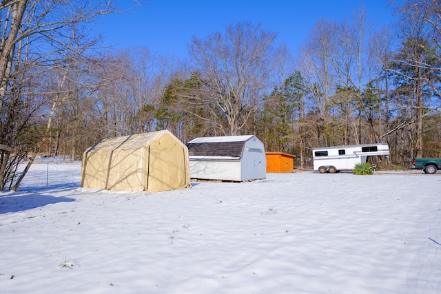 yard layered in snow featuring a storage shed