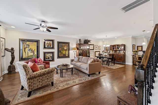 living room featuring ornamental molding, dark wood-type flooring, and ceiling fan with notable chandelier