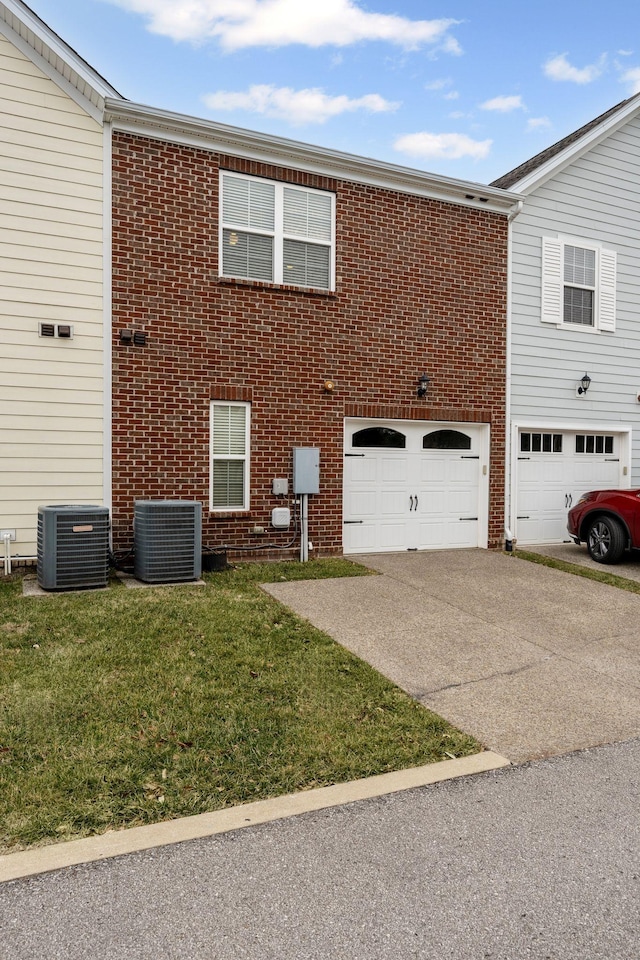 view of front of house with cooling unit, a garage, and a front yard