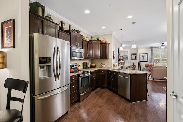 kitchen with sink, hanging light fixtures, appliances with stainless steel finishes, kitchen peninsula, and light stone countertops