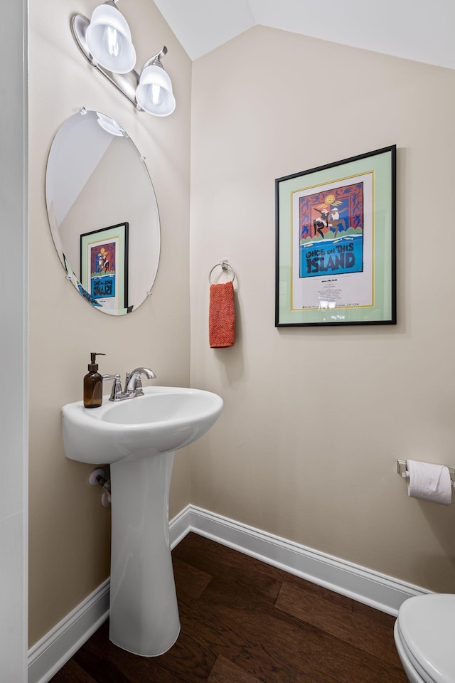 bathroom with hardwood / wood-style flooring, toilet, and vaulted ceiling