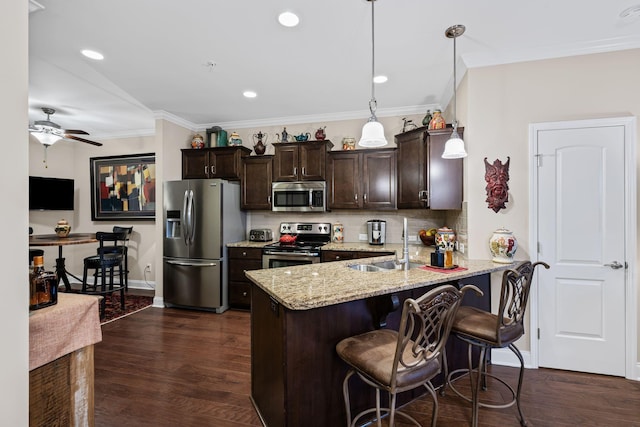 kitchen featuring appliances with stainless steel finishes, decorative light fixtures, sink, a breakfast bar area, and kitchen peninsula