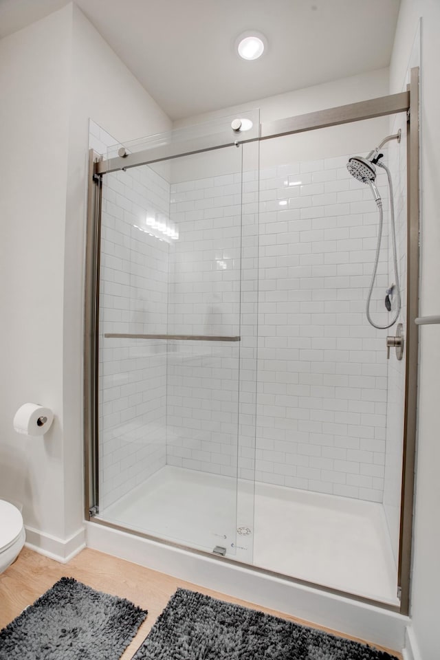 bathroom with a shower with shower door and toilet