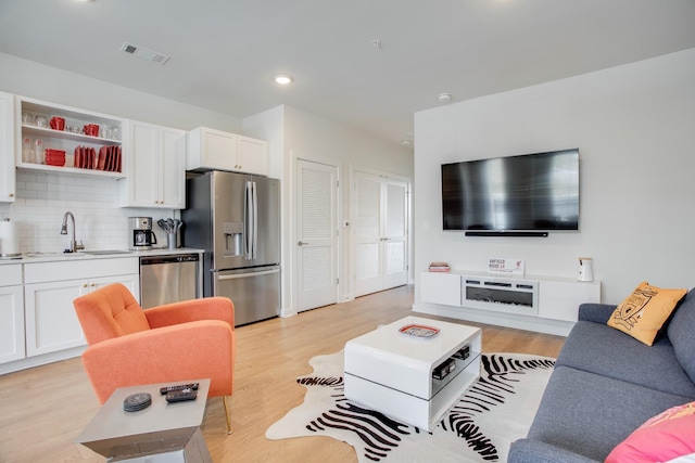 living room with sink and light wood-type flooring