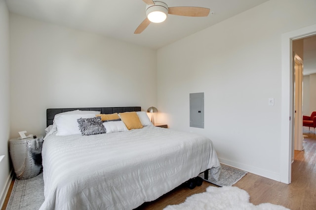 bedroom featuring ceiling fan, electric panel, and hardwood / wood-style floors