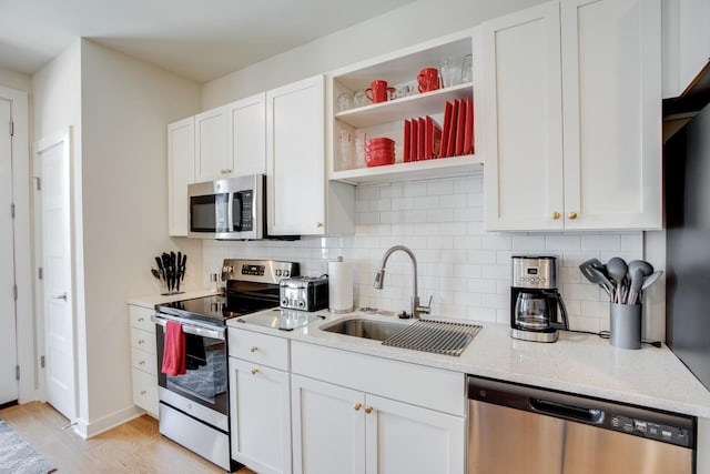 kitchen featuring appliances with stainless steel finishes, sink, white cabinets, and light stone counters