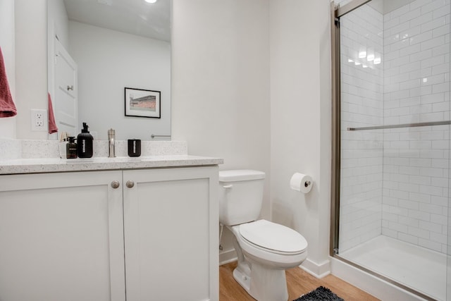 bathroom featuring vanity, wood-type flooring, toilet, and walk in shower