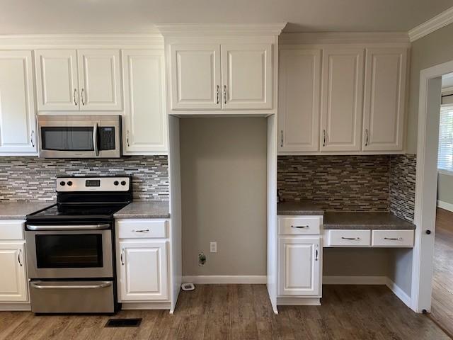 kitchen featuring white cabinetry, backsplash, dark hardwood / wood-style flooring, ornamental molding, and stainless steel appliances