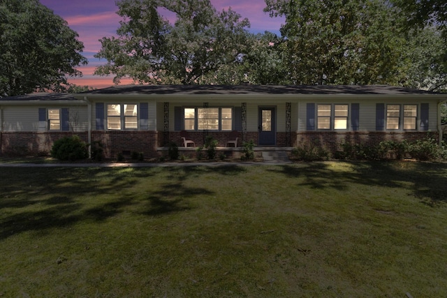 ranch-style house featuring brick siding and a yard