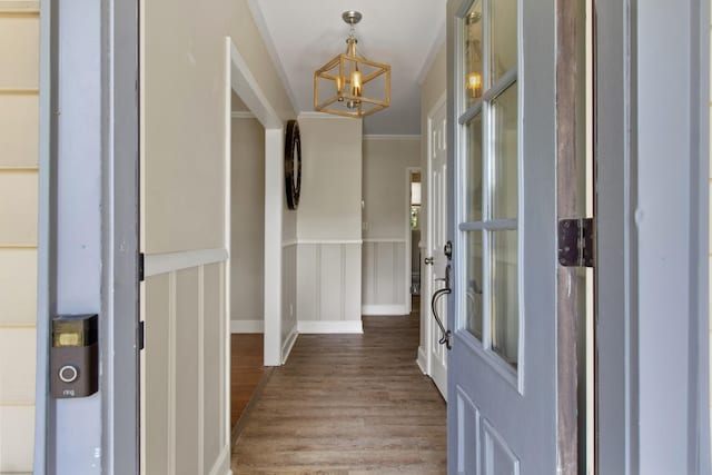 entryway with hardwood / wood-style floors, a notable chandelier, and ornamental molding