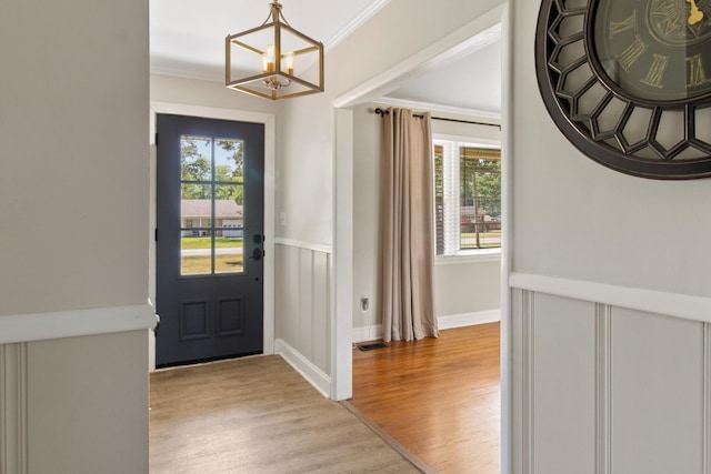 foyer entrance featuring light hardwood / wood-style flooring, ornamental molding, and a healthy amount of sunlight