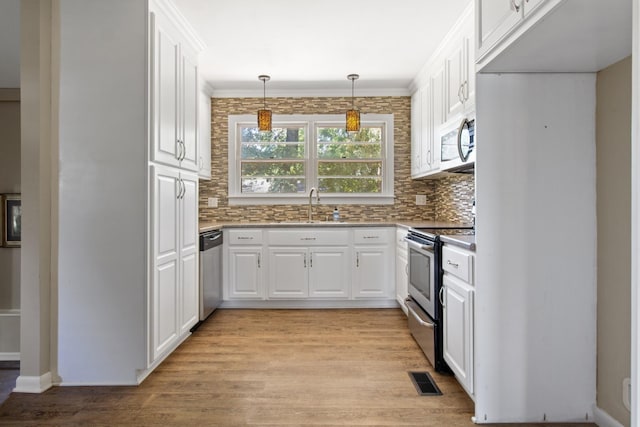 kitchen with sink, decorative light fixtures, light hardwood / wood-style flooring, appliances with stainless steel finishes, and white cabinets