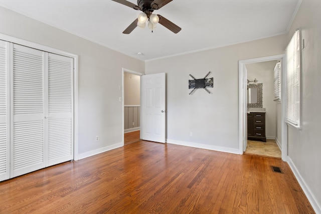 unfurnished bedroom with hardwood / wood-style flooring, ornamental molding, ceiling fan, and a closet