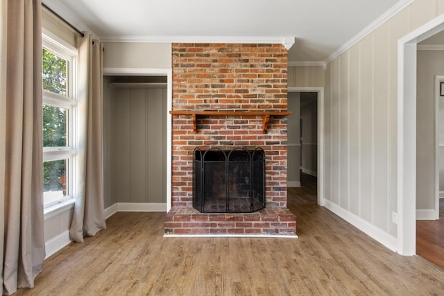 unfurnished living room featuring ornamental molding, a brick fireplace, and light hardwood / wood-style floors