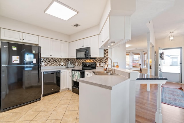 kitchen with sink, white cabinetry, kitchen peninsula, decorative backsplash, and black appliances