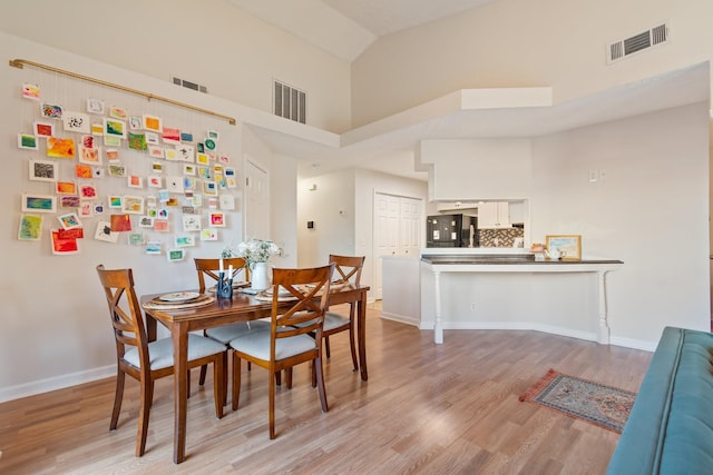 dining room featuring light hardwood / wood-style flooring and high vaulted ceiling